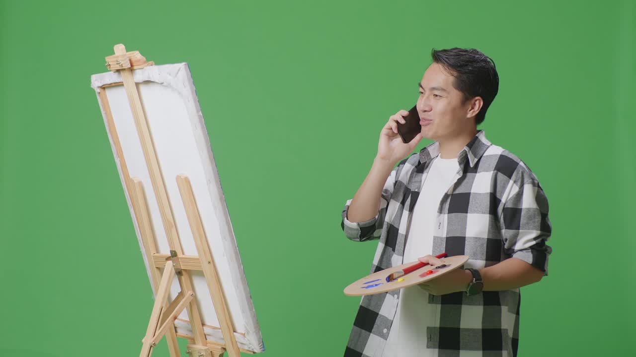 캔버스를 보면서 휴대전화로 이야기하는 예술가