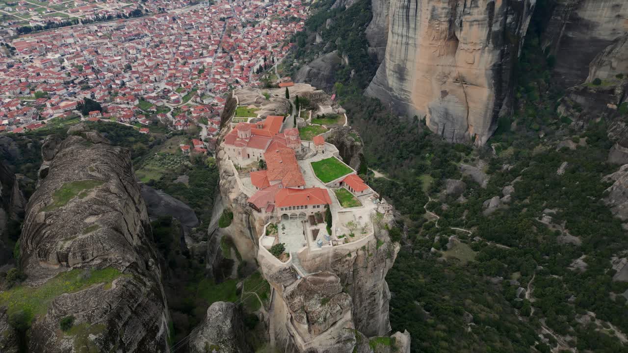 Top down drone establishing of Meteora monastery with red roofs atop rocky mountain ridge