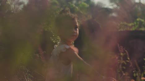 Low-angle-handheld-shot-through-plants-in-garden-of-girl-with-flowers-in-her-hand-while-picking-more-flowers-on-a-sunny-summer-day