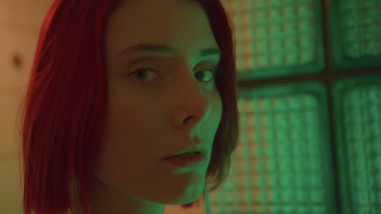 retrato de una mujer joven en luz coloreada contra bloques de vidrio texturizado