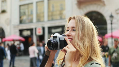 Vista-De-Cerca-De-Una-Turista-Rubia-Caucásica-Tomando-Fotos-Con-Una-Cámara-En-El-Centro-De-La-Ciudad