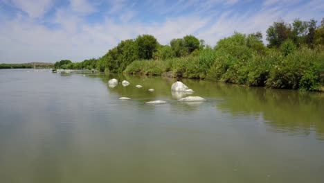 Drone-Flying-over-river-with-big-white-stones-and-birds