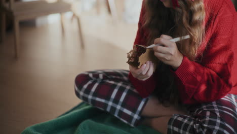 woman coloring cardboard house during christmas at home