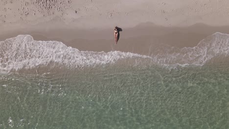 overhead view of young bikini woman centered on beach with clear water