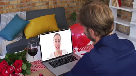 Caucasian-couple-on-a-valentines-date-video-call-man-waving-to-woman-on-screen