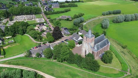 Orbit-view-of-little-church-in-grassland,-small-village