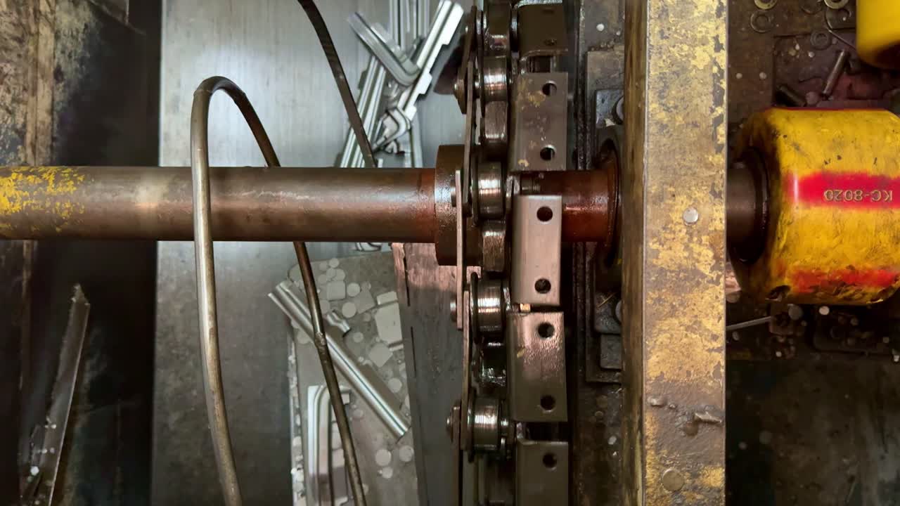 Industrial machine with rotating chain and metal shaft in a factory. Heavy-duty mechanical components in operation