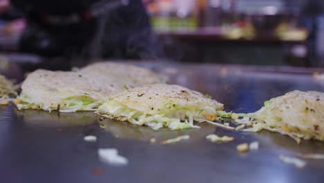 okonomiyaki, japanese vegetable and noodle pancake on teppan grill