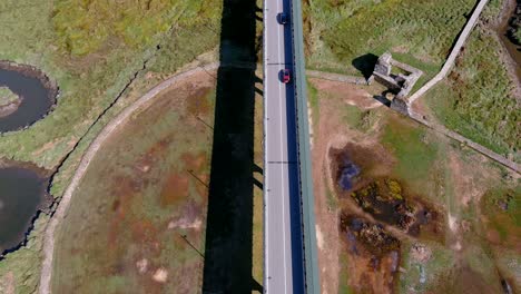 Coches-Circulando-Por-El-Puente-Sobre-El-Río-Ulla-En-Sequía-Con-La-Naturaleza-Que-Emerge-Del-Cauce,-Tarde-Soleada,-Zumbido-Rodante-Disparado-Hacia-Arriba-Cenital