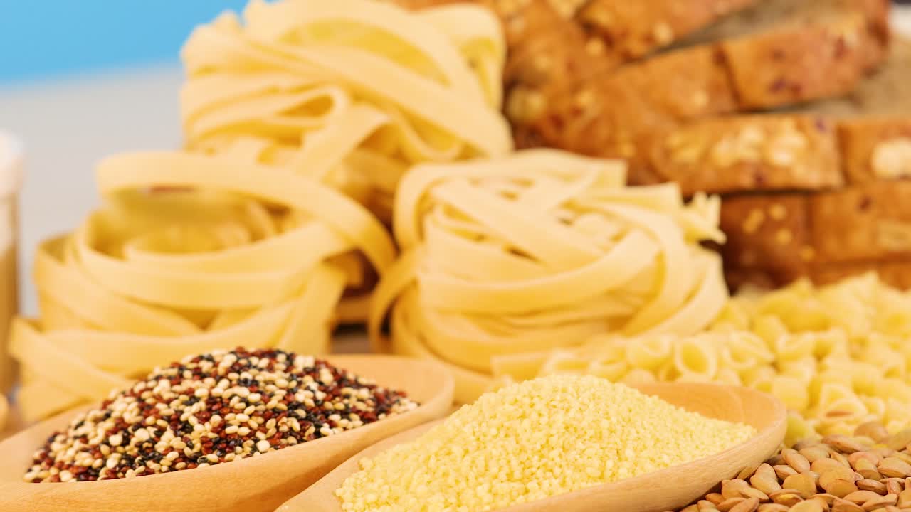 A vibrant arrangement of grains, pasta, and bread under bright lighting, showcasing diverse textures and colors