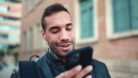 Young-man-recording-a-voice-message-on-smartphone-outdoors.