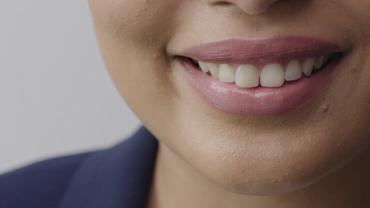 vicino labbra di donna sorridente felice che indossa rossetto lucido che mostra denti sani