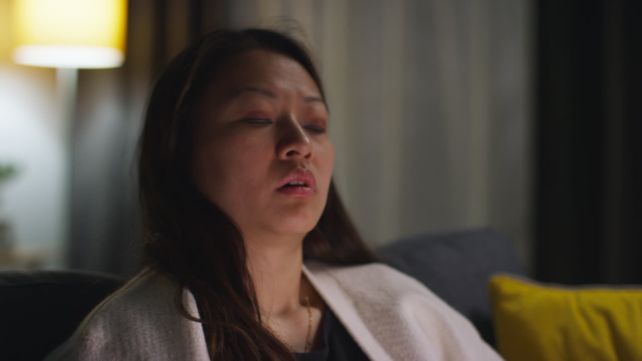 스트레스를 받고 불안한 여성이 집에서 저녁을 보내고 소파에 앉아 인터넷이나 소셜 미디어 뉴스 또는 노트북에서 금융 이야기에 반응합니다.