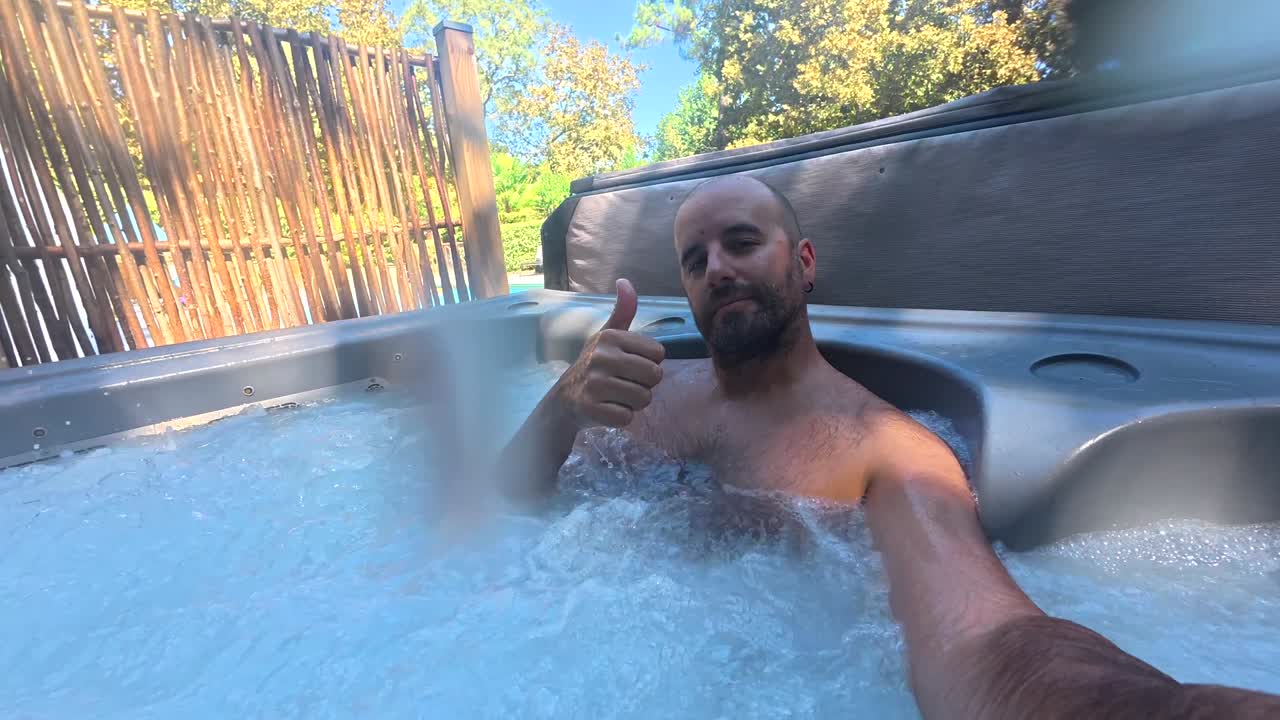 Uomo che si rilassa in una vasca idromassaggio esterna in una giornata di sole