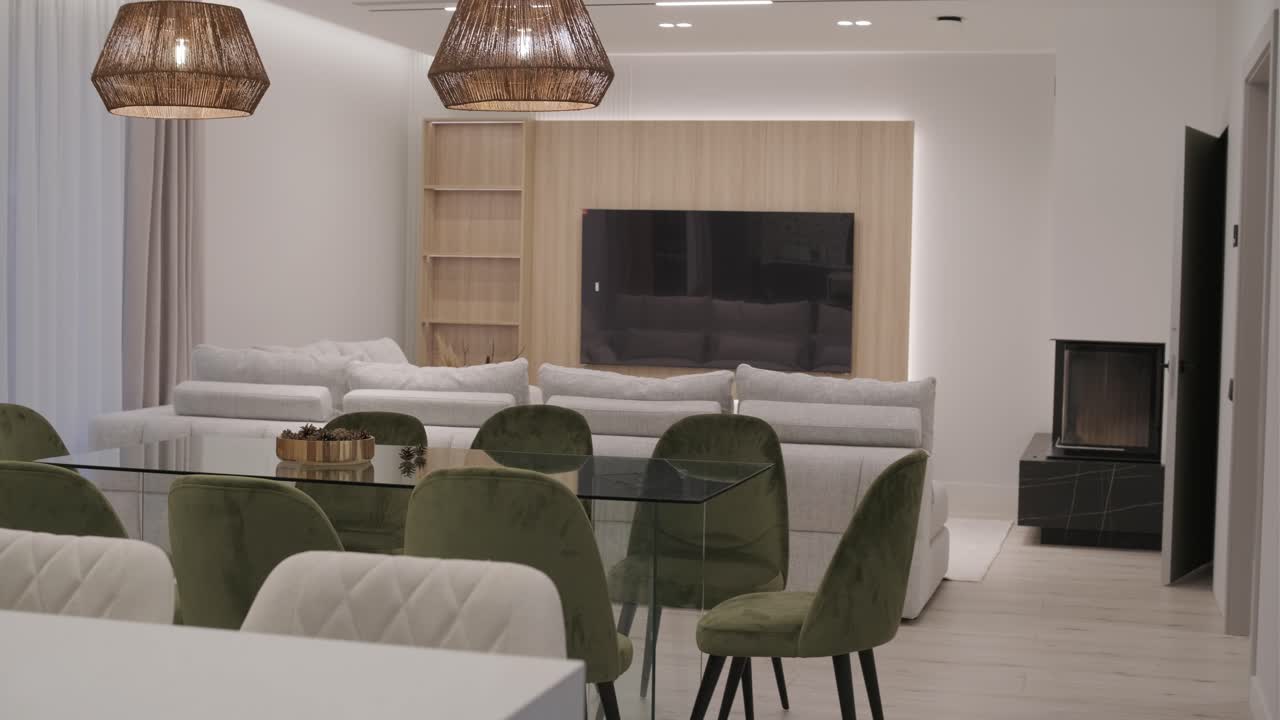 espacio de vida elegantemente diseñado, acentos de madera natural complementan el sofá gris suave y sillas de terciopelo verde, unificados bajo una cálida iluminación colgante