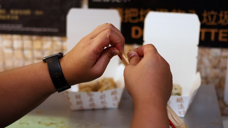Mani che aprono e usano le bacchette per mangiare