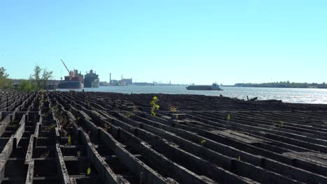 Barge-on-the-River-in-New-Orleans-with-old-wooden-dock-moorings-on-shore