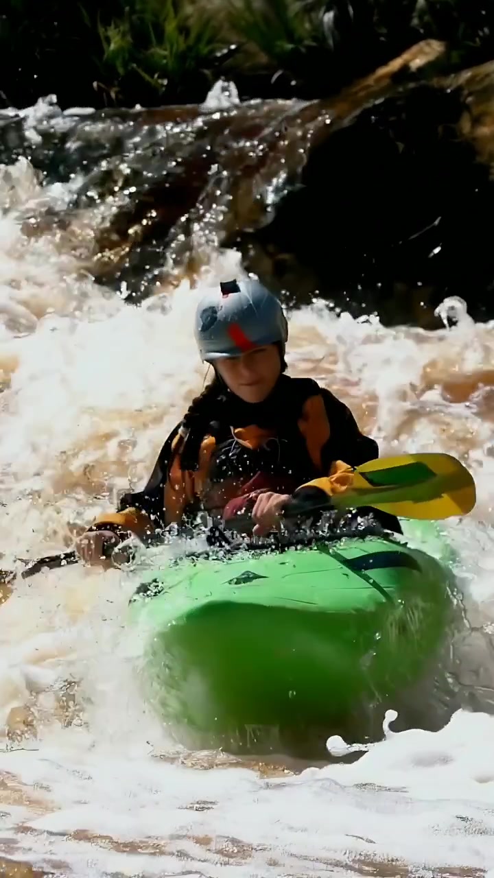 Video verticale: Kayaker spinto dalla corrente che pagaia e si stabilizza in una rapida del fiume, mantenendosi fermo con il casco.