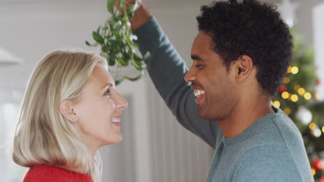 Una-Pareja-Amorosa-Besándose-Bajo-El-Muérdago-En-Una-Casa-Decorada-Para-Navidad