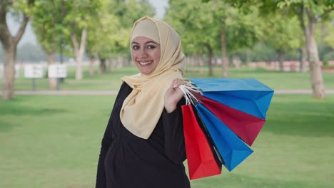 happy muslim woman doing shopping in park