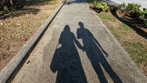 Sombra-De-Una-Pareja-Comprometida-Caminando-En-La-Acera-En-Un-Día-Soleado,-La-Mujer-Pidiendo-Tomarse-De-La-Mano-En-Señal-De-Amor,-Concepto-De-Relación-Poco-Saludable