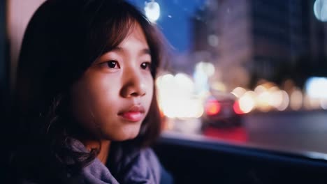 young woman looking out the window of a car at night in the city