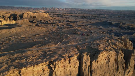 drone shot of moonscape overlook and desert landscape of utah usa, vehicles on hill at golden hour sunlight