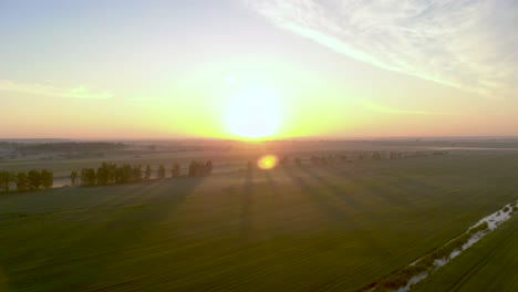 Bright-Colorful-Sunset-on-Horizon-of-Latvia-Agricultural-Countryside---Aerial-Pullback-View