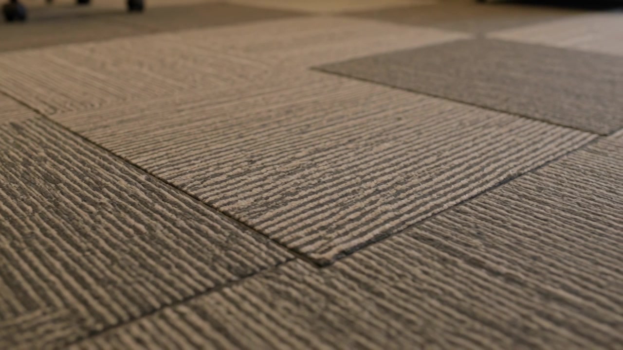 Pulling back camera revealing carpet seam in office, showing darker tile, fibers and caster wheels