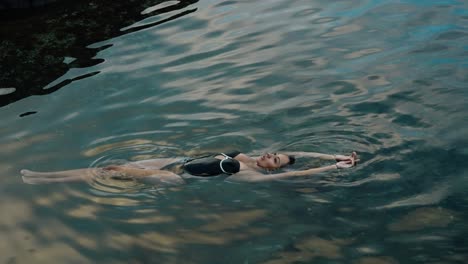 a woman floats peacefully in crystal-clear volcanic waters in seixal, madeira, surrounded by soft ripples and natural reflections.