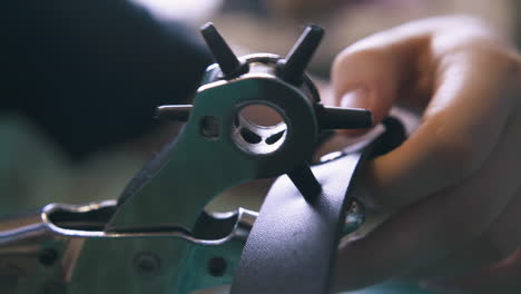 tailor makes holes in belt with special punch pliers closeup