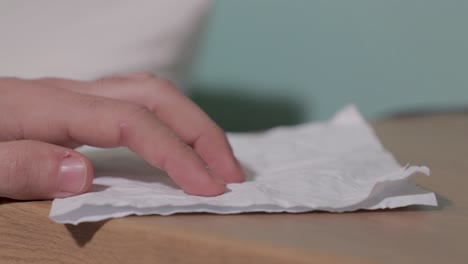 pan right to left shot of man taking a rinkled page from a table