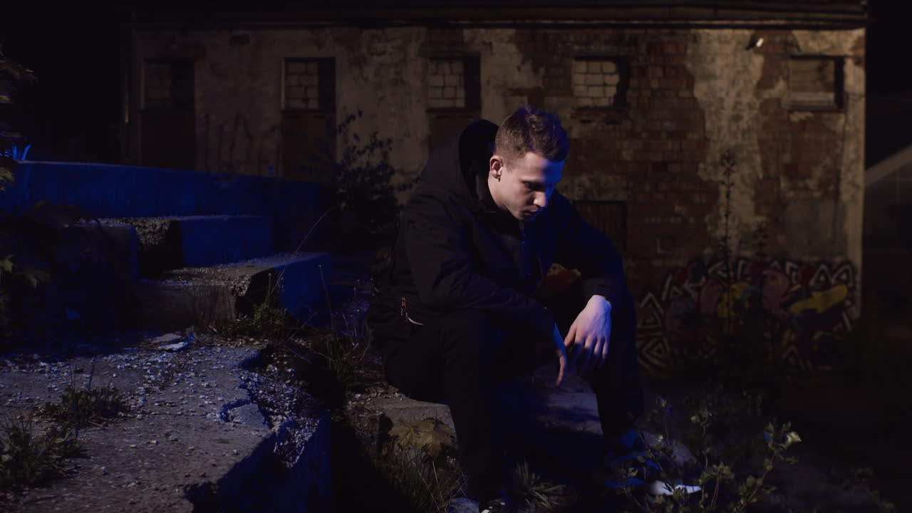 Man Sitting Alone at Night in an Abandoned Building