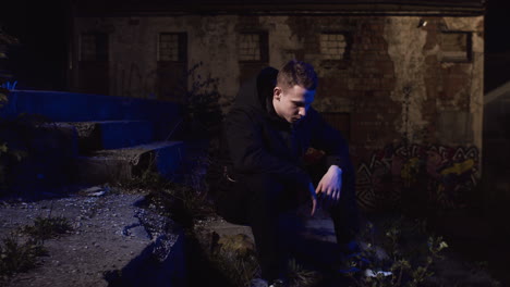 man sitting alone at night in an abandoned building