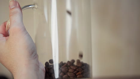 barista hand fill coffee beans into plastic cup, ready for grinding