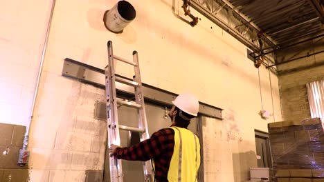 blue collar worker climbing a ladder to perform maintenance work