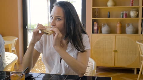 mujer morena comiendo pizza sentada en una mesa de restaurante con sus amigos