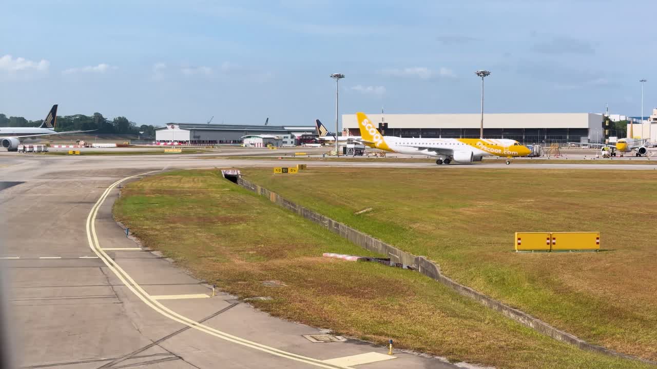 Vidvinkelbilde av flere passasjerfly som takser over en flyplassrullebane i sterkt dagslys.