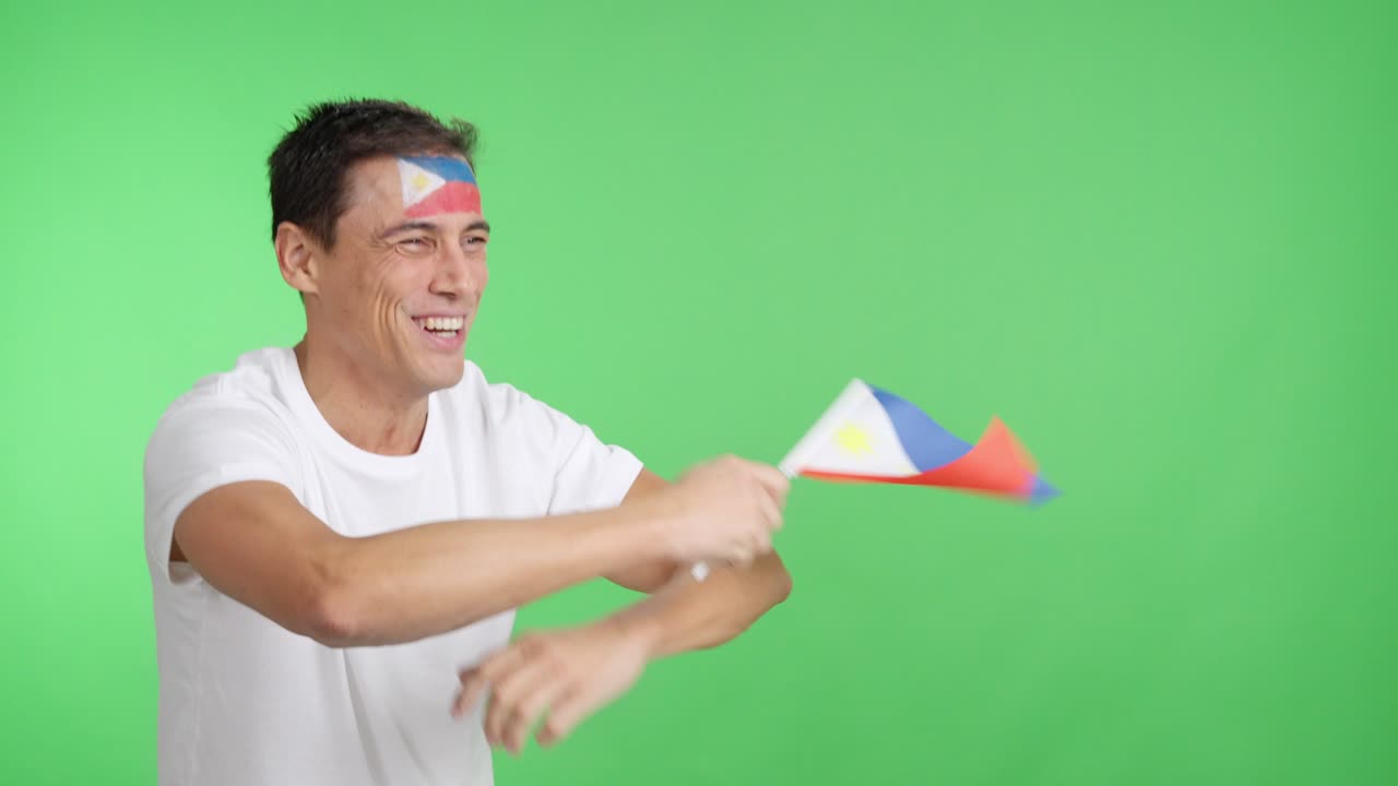 Man cheering for Philippines waving a national flag looking away