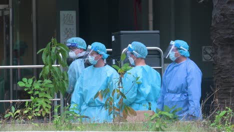 se ve a los trabajadores de la salud con trajes de ppe de pie vigilantes fuera de un edificio puesto bajo cerradura después de que un gran número de residentes resultaron positivos para el coronavirus covid-19