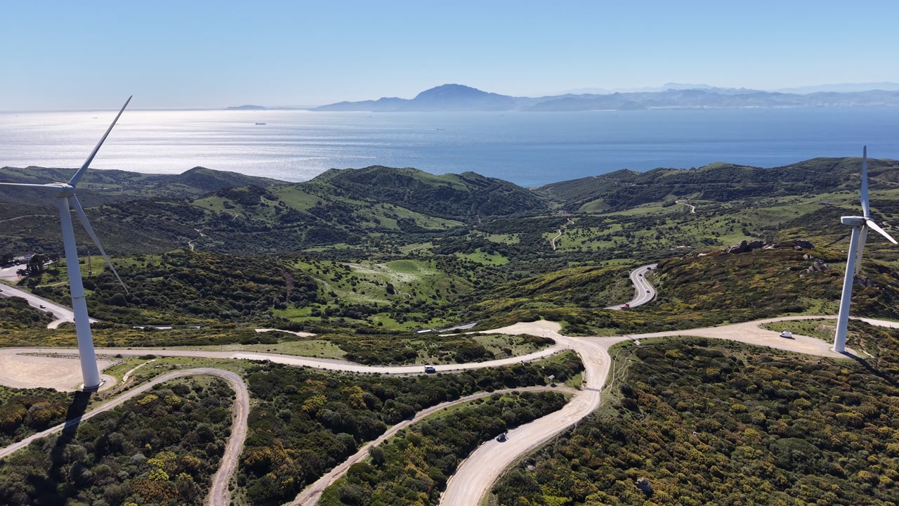 Aerial panorama of wind turbines on the hills of Andalusia, looking south towards the Strait of Gibraltar and the Moroccan mountains.