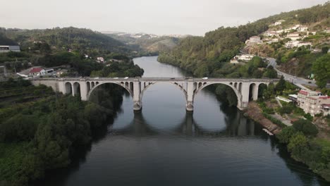 panoramic aerial circling drone view of famous ponte de pedra bridge over douro river at entre os rios city in portugal