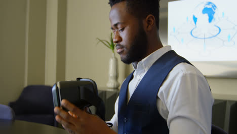 Side-view-of-young-black-businessman-wearing-virtual-reality-headset-while-working-on-laptop-4k