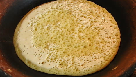 food shot of some homemade traditional moroccan baghrer in clay fryer , pancakes baghrir or crapes with 1000 holes