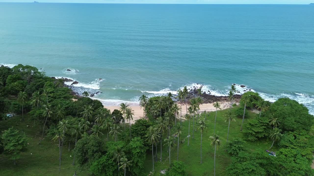 Stunning aerial drone footage semi orbit over palm forest on tropical paradise island, uncovering a remote sandy beach with turquoise ocean waters on Koh Lanta, Thailand. South East Asia