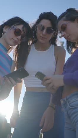 three young women using their smartphones outdoors