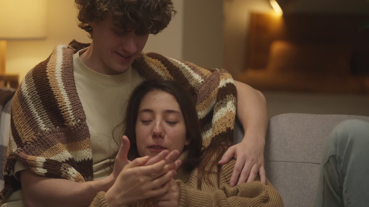 Couple cuddling under a blanket on the couch