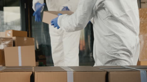 personas con trajes protectores descargan una furgoneta con cajas