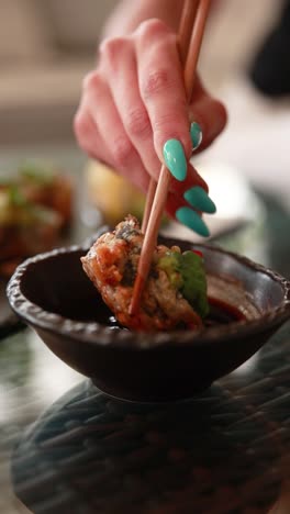 mujer comiendo sushi con palillos