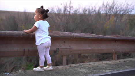 Pequeña-Niña-Negra-Sudafricana-Parada-En-Un-Puente-Bajo-En-Un-Paisaje-Invernal